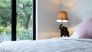 A bedroom with a bed, a lamp, and a window with a view of trees. - A stylish house for 6 in the heart of Newport, Pembrokeshire (Newport)