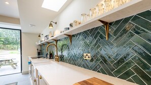 A kitchen with a white countertop, a wooden cutting board, a herringbone-patterned backsplash, and a skylight. - A stylish house for 6 in the heart of Newport, Pembrokeshire (Newport)