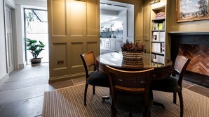 A dining area with a round table, chairs, a potted plant, and a fireplace. - A stylish house for 6 in the heart of Newport, Pembrokeshire (Newport)