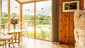 A room with a large glass door leading to a garden, wooden walls, a framed picture, and a stone feature. - A beautiful barn conversion nestled amongst the hills.. (Crymych)