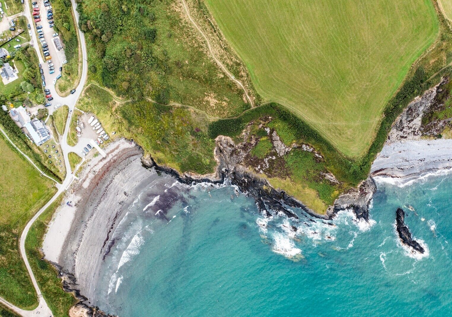A coastal area with a road, parking lot, and buildings.