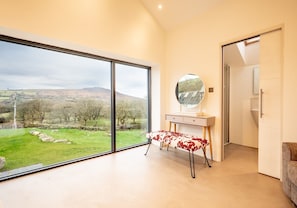 A modern room with a large window offering a view of a green landscape and hills.