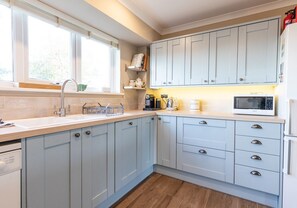A modern kitchen with light blue cabinets, a stainless steel sink, a microwave, and a coffee maker.