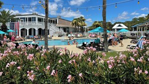 A pool area with lounge chairs, a swimming pool, and a building with a white facade and arched windows. - Fripper Upper: 1st Floor, Just for TWO, MARSH Views, FREE Coffee/Tea/Creamer, Club Cards Available! (Fripp Island)