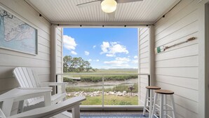 A room with a view of a grassy field and trees, a map on the wall, a ceiling fan, and a table with chairs. - Fripper Upper: 1st Floor, Just for TWO, MARSH Views, FREE Coffee/Tea/Creamer, Club Cards Available! (Fripp Island)