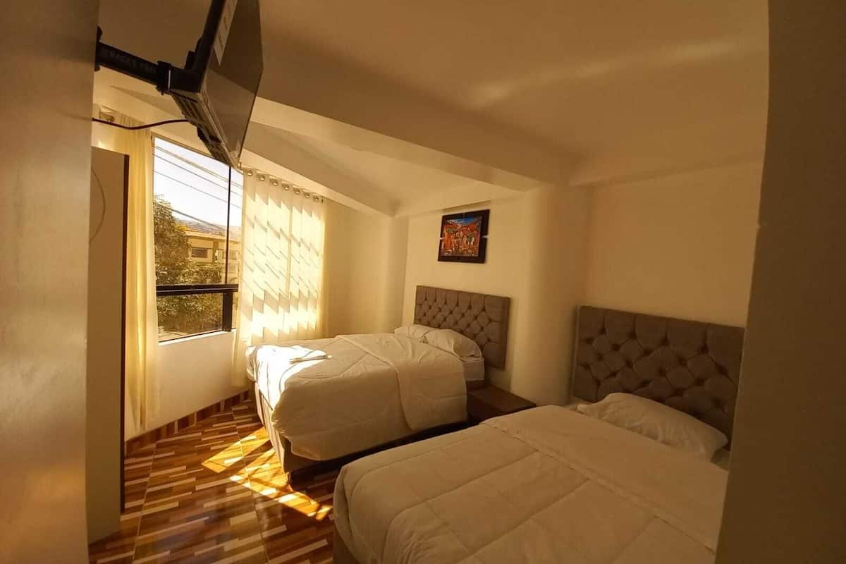 A hotel room with two beds, a window with blinds, a painting on the wall, and a patterned floor.