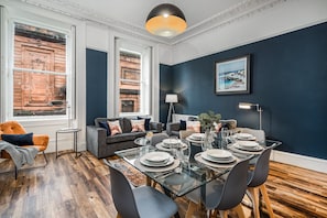 Un coin repas avec une table en verre dressée pour six personnes, entourée de chaises grises.
