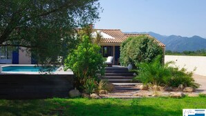 A house with a swimming pool, surrounded by greenery and mountains in the background.