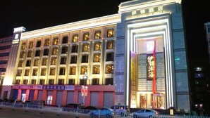 Un hôtel à plusieurs étages, doté d’une entrée imposante et d’une enseigne lumineuse.