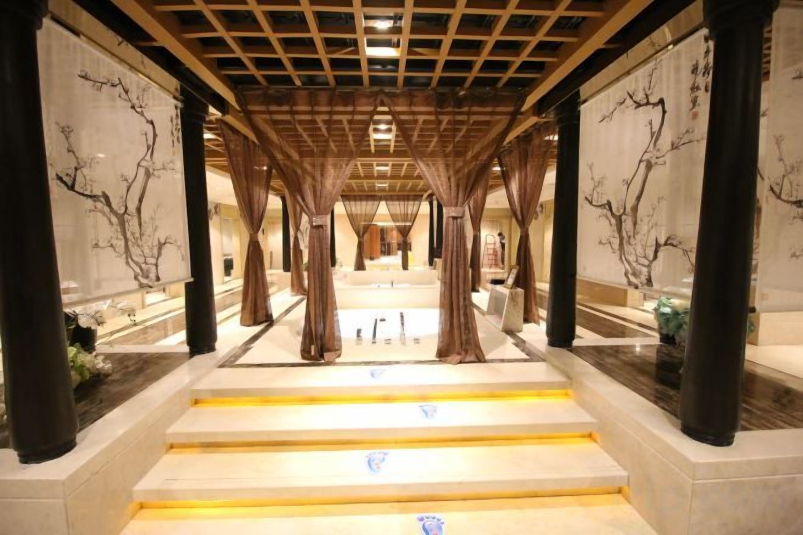 A corridor with a wooden ceiling, marble steps, and columns with artwork.