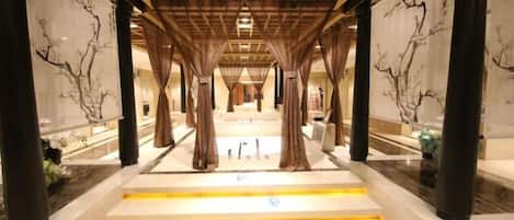 A corridor with a wooden ceiling, marble steps, and columns with artwork.
