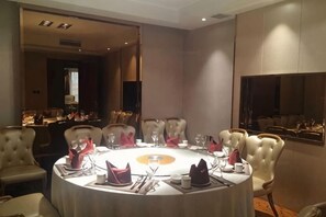 A conference room with a round table, chairs, and a large mirror. - Yi Jin Hotel (Harbin)