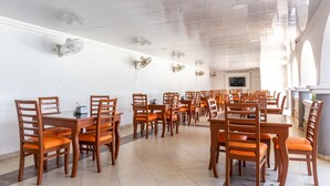 A spacious dining area with multiple tables and chairs, a flat-screen TV mounted on the wall, and decorative wall sconces. - Hotel Damar Valledupar (Valledupar)