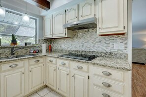 Kitchen features white cabinetry, stainless steel range hood, and granite countertop.