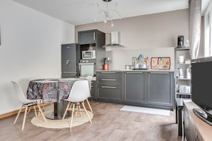 Une cuisine compacte avec un coin repas, équipée d’un four à micro-ondes, d’un four traditionnel et de meubles de rangement modernes.