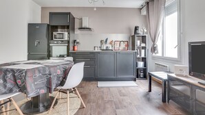 A compact kitchen with a dining area, a built-in microwave, a gas stove, and a small refrigerator. - L'Amarillo - Apt 1 chambre vielle ville (Nancy)