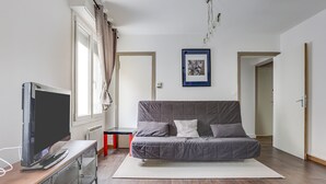 A modern bedroom with a grey sofa, a TV on a wooden table, and a framed picture on the wall. - L'Amarillo - Apt 1 chambre vielle ville (Nancy)
