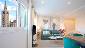 Un salon moderne avec une grande fenêtre, un canapé vert, une table à manger et un téléviseur.