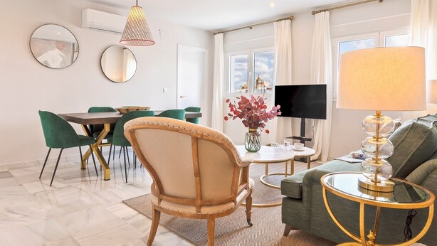 Un salon moderne comprenant un coin repas, un canapé, un téléviseur et une lampe.