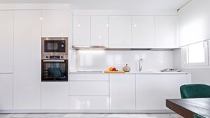 Une cuisine moderne avec des meubles blancs, un four encastré et un four à micro-ondes.