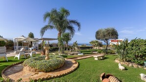 A well-maintained garden with a circular flower bed, outdoor seating, and a gazebo. - Azzuro Villa by Estia (Hersonissos)