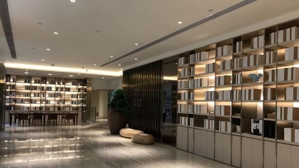 A modern library with bookshelves, a seating area, and a large potted plant. - JI Hotel (Wuhan Hankou Railway Station Tangjiadun) (Wuhan)