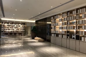 A modern library with bookshelves, a seating area, and a large potted plant. - JI Hotel (Wuhan Hankou Railway Station Tangjiadun) (Wuhan)