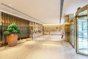 A modern hotel lobby with a reception desk, a large potted plant, and a bookshelf. - JI Hotel (Wuhan Hankou Railway Station Tangjiadun) (Wuhan)