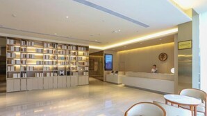 A modern hotel lobby with a reception desk, seating area, and a bookshelf. - JI Hotel (Wuhan Hankou Railway Station Tangjiadun) (Wuhan)