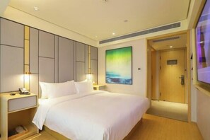 A hotel room with a large bed, a nightstand, a wall-mounted TV, and a door to the bathroom. - JI Hotel (Wuhan Hankou Railway Station Tangjiadun) (Wuhan)