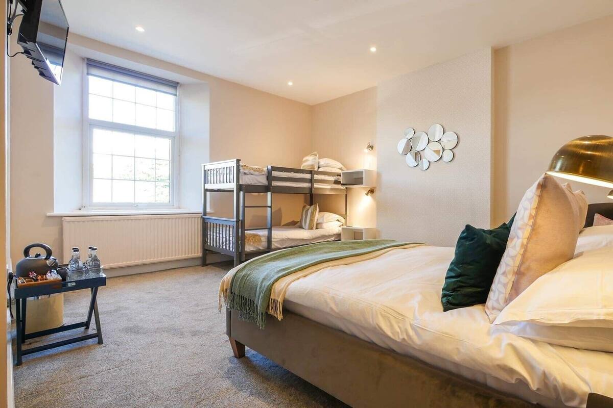 A bedroom with bunk beds, a bedside table with a lamp, and a window with blinds.