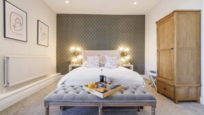 A bedroom with a large bed, a wooden wardrobe, a bedside table with a lamp, and a tray with breakfast items. - The Greenhead Hotel (Brampton)
