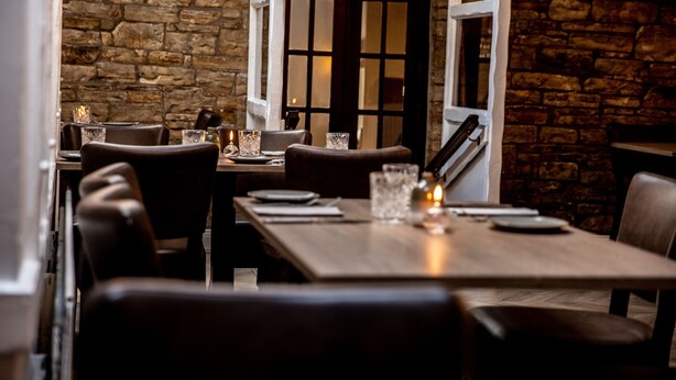 A restaurant with a stone wall interior, wooden tables, and leather chairs. - The Greenhead Hotel (Brampton)