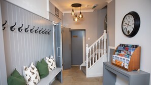 A hallway with a bench, a coat rack, a private door, a staircase, and a magazine rack. - The Greenhead Hotel (Brampton)