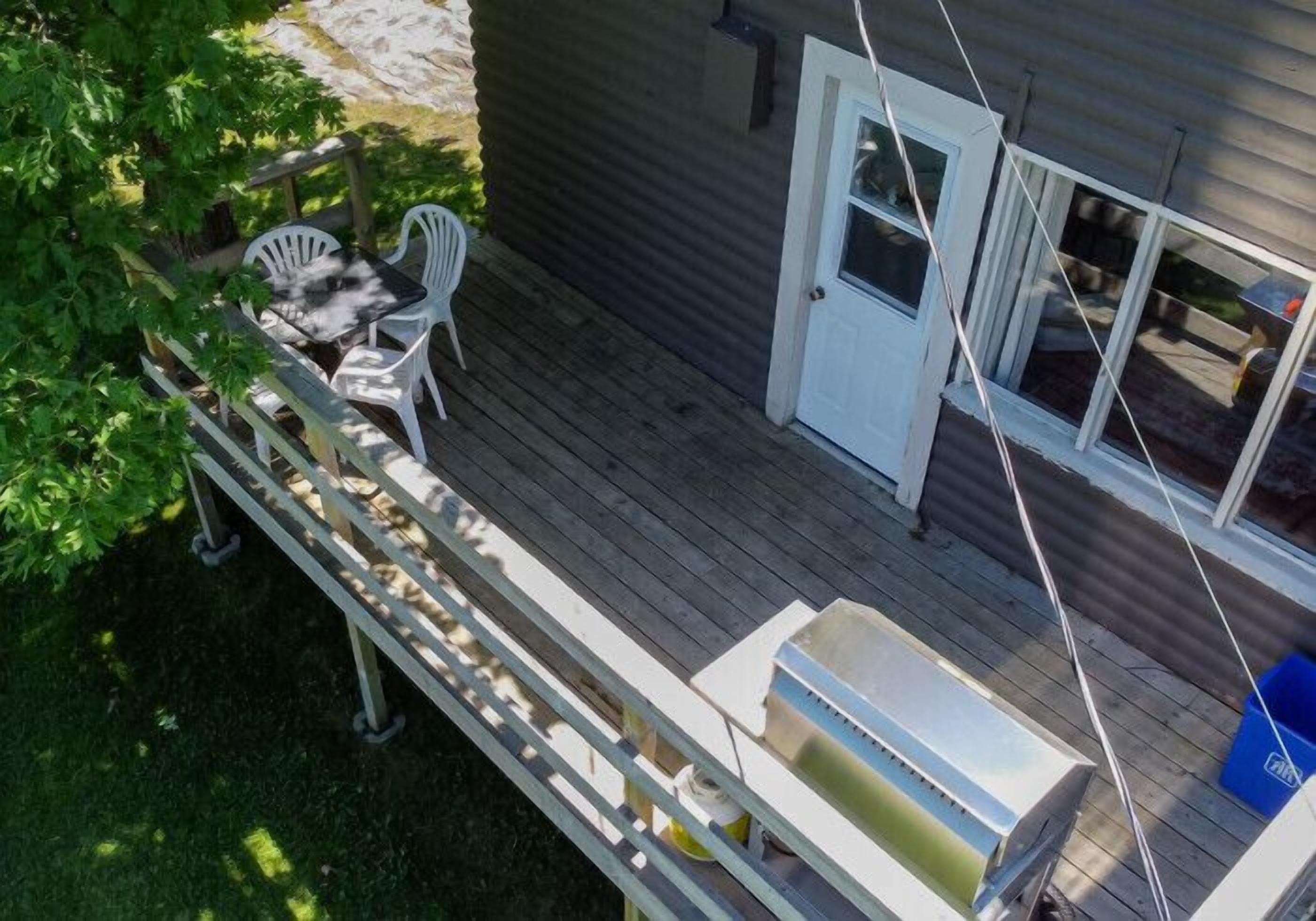 A deck with outdoor furniture, a grill, and a door to a house.