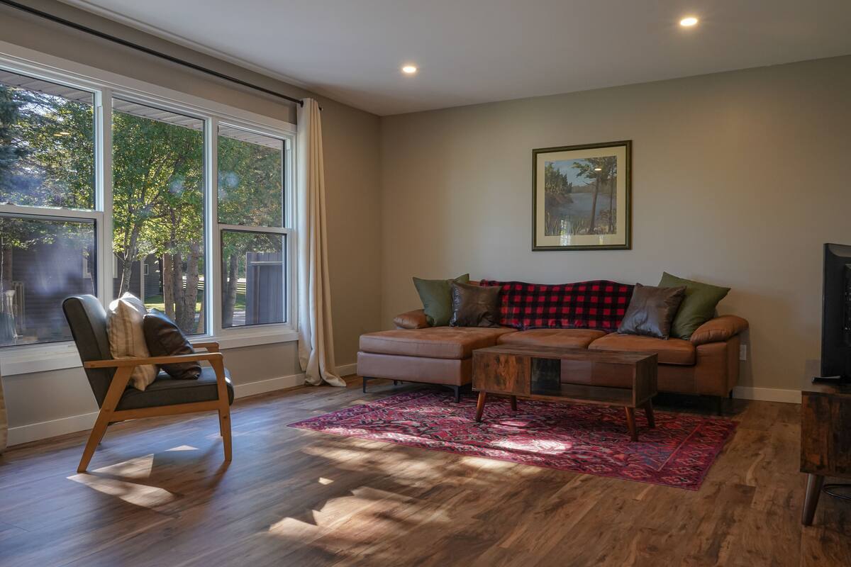 Una sala de estar con un ventanal grande, un sofá, un sillón y una mesita de centro.