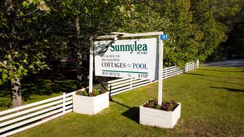 Schild für das Sunnylea Resort mit Annehmlichkeiten wie Cottages, einem Pool, Bootsverleih und einem Spazierweg.