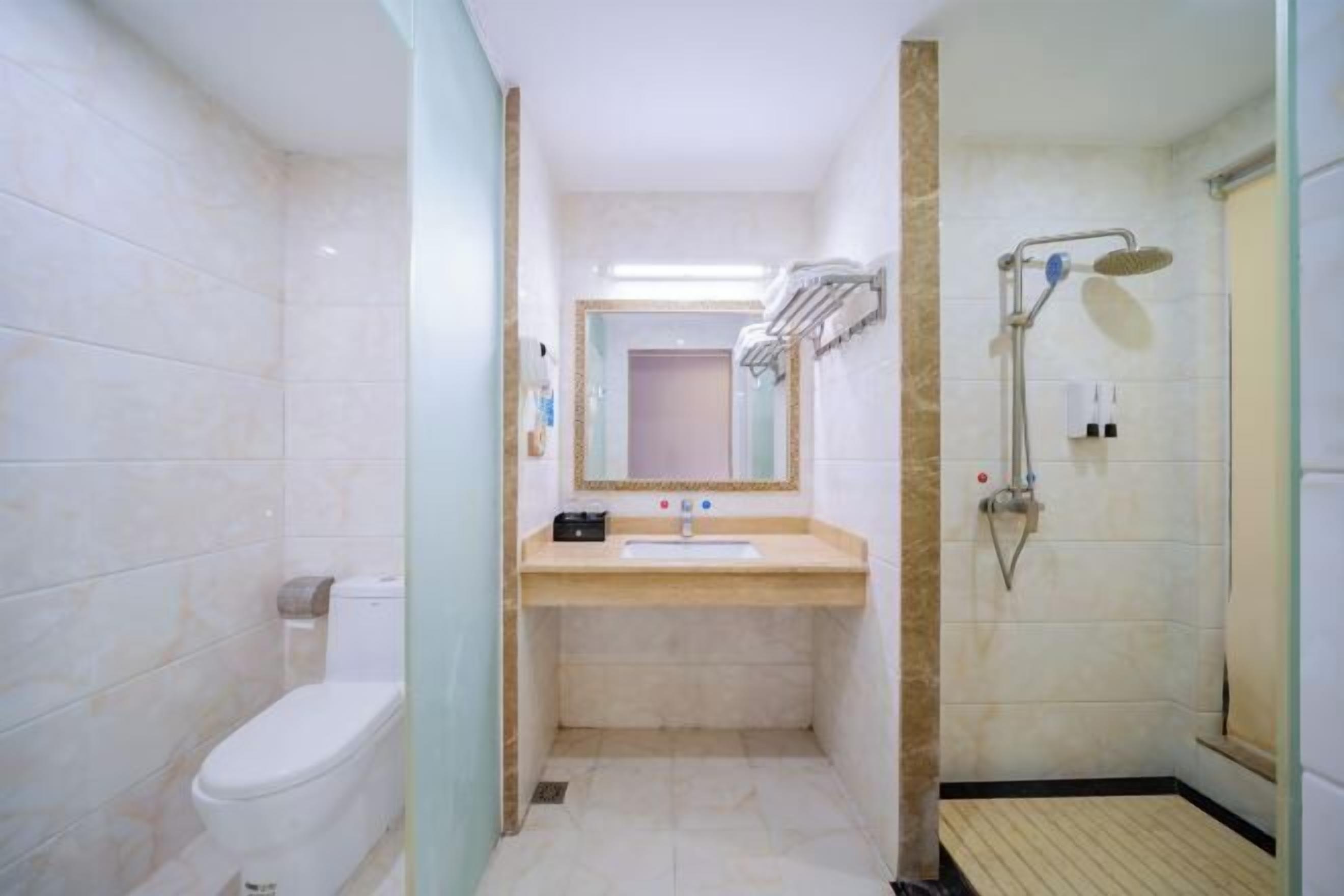 Un baño con inodoro, lavabo, espejo y ducha.