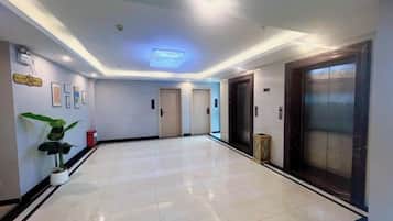 A hotel lobby with a tiled floor, a reception desk, and an elevator.