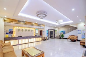 A hotel lobby with a reception desk, seating area, and a staircase. - Zhaoqing Jinyuan Hotel (Zhaoqing)