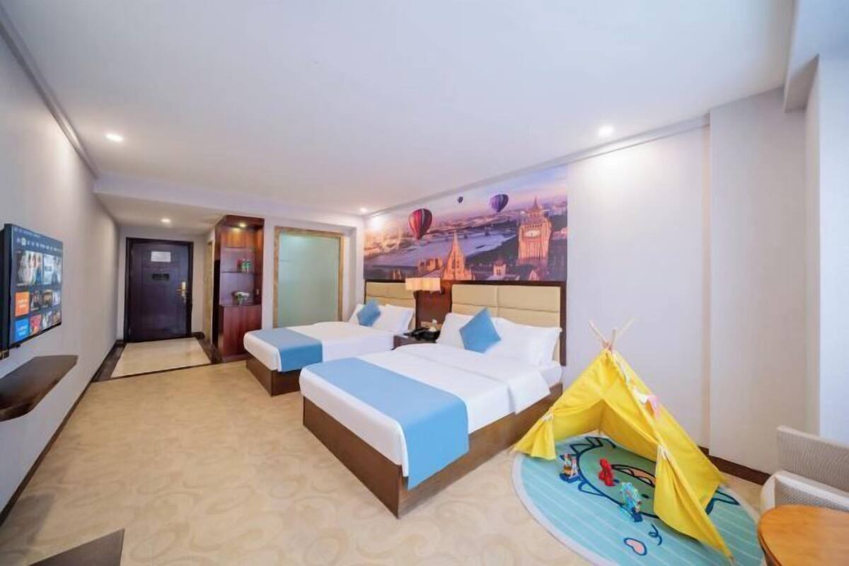 A hotel room with two beds, a television, a wall mural, and a tent.