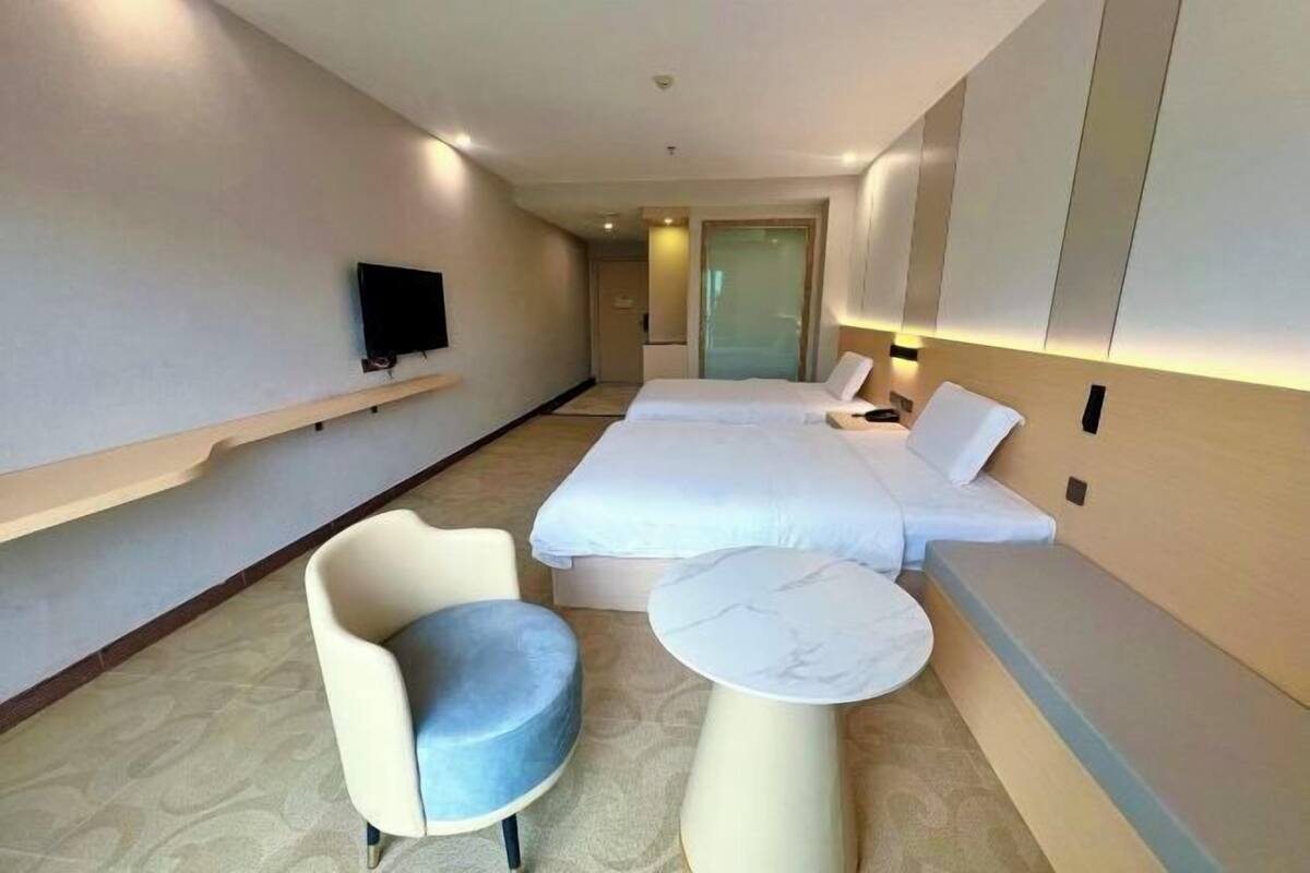 A hotel room with a bed, a TV, a chair, and a small table.