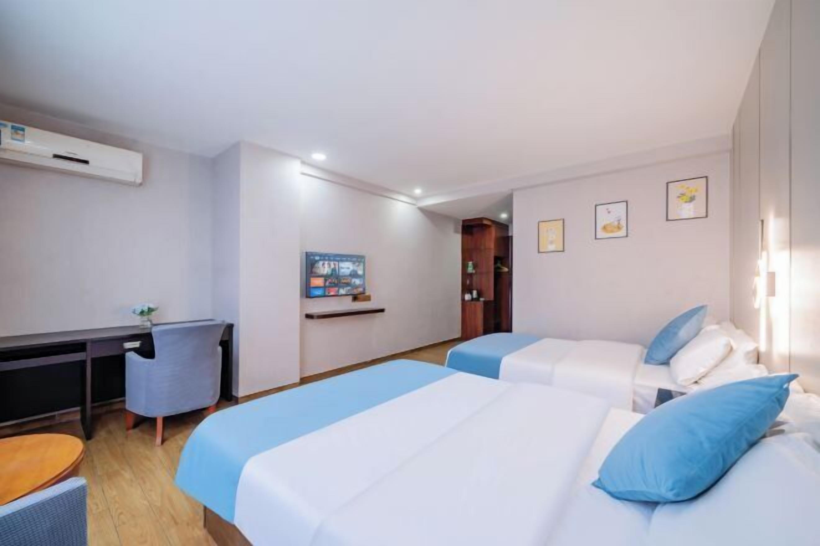 Ett hotellrum med två sängar, ett skrivbord, en stol, en TV och ett litet bord.