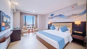 A hotel room with a large bed, a desk, a chair, a TV, and a window with curtains. - Zhaoqing Jinyuan Hotel (Zhaoqing)