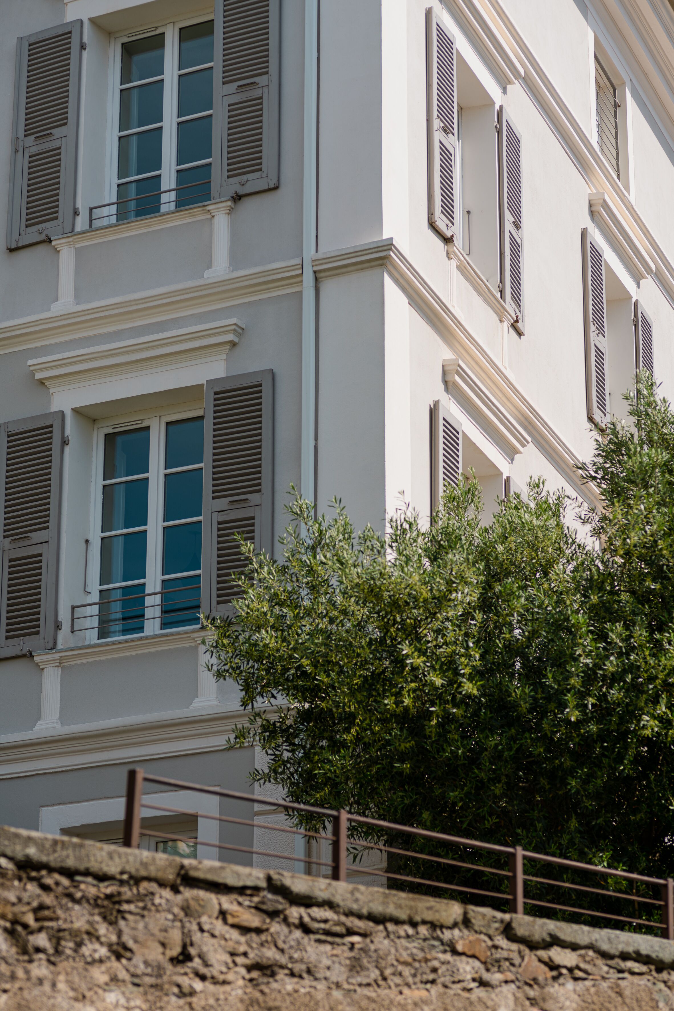 Un immeuble à plusieurs étages, aux murs blancs et aux fenêtres dotées de volets.