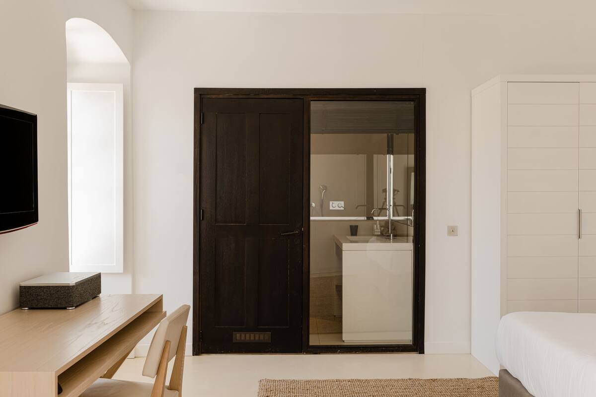 A bedroom with a bed, a desk, a chair, and a wardrobe.