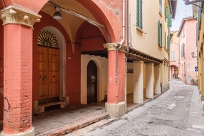 A narrow street with buildings featuring arched doorways and columns. - Casa del Mare (Bologna)
