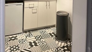 A compact kitchen with white cabinets, a microwave, a coffee maker, and a trash bin. - Le Bonnie- Ground floor studio for 2 persons (Honfleur)