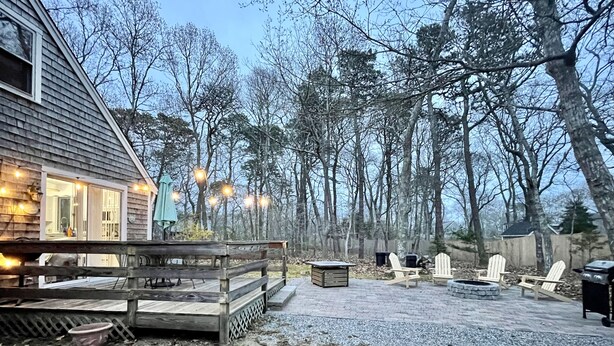 Ein Holzhaus mit Terrasse, Sitzgelegenheiten im Freien und einem Feuerkorb.