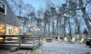 Una casa di legno con veranda, area salotto esterna e un braciere.